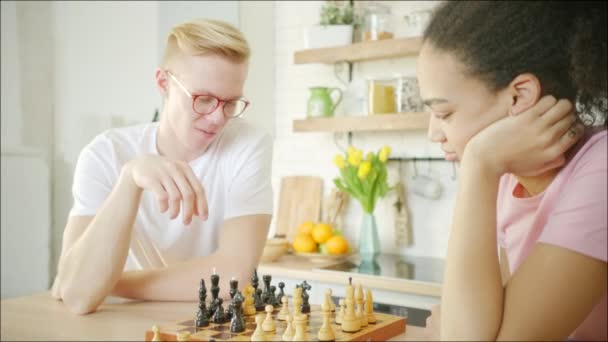 Jonge blonde man speelt schaken met afrikaanse amerikaanse jonge vrouw — Stockvideo