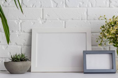 Bir tuğla vintage arka plan üzerinde Ahşap fotoğraf çerçeveleri, bir vazo papatyalar