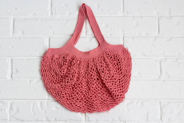 Knitted string bag weighs on a vintage brick wall