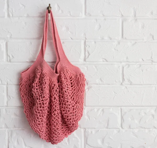 Knitted string bag weighs on a vintage brick wall