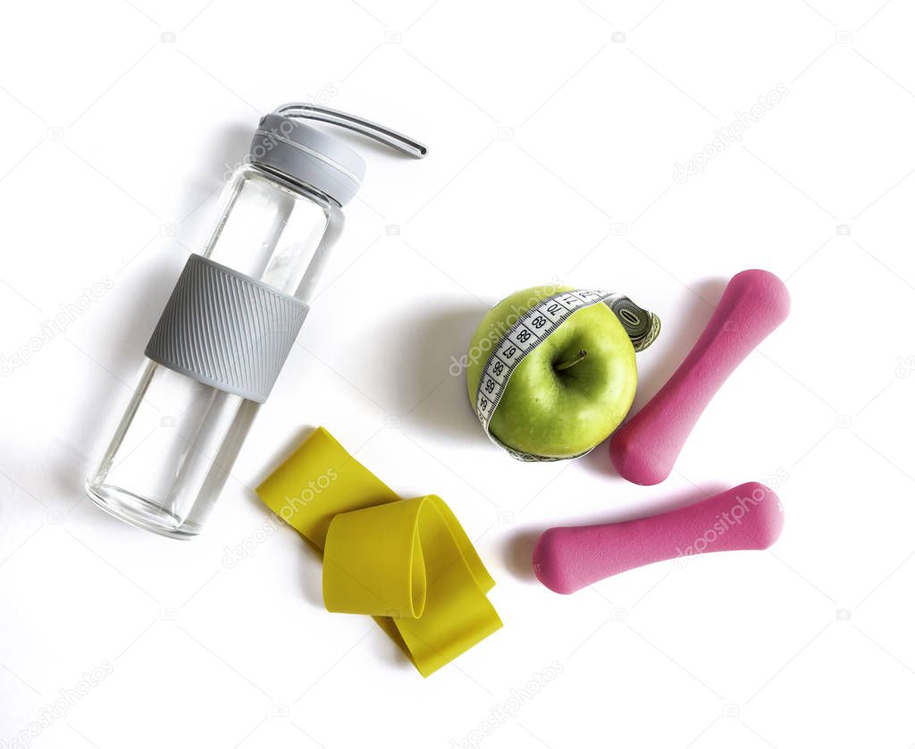Apple with measuring tape, fitness elastic band, water bottle and dumbbells