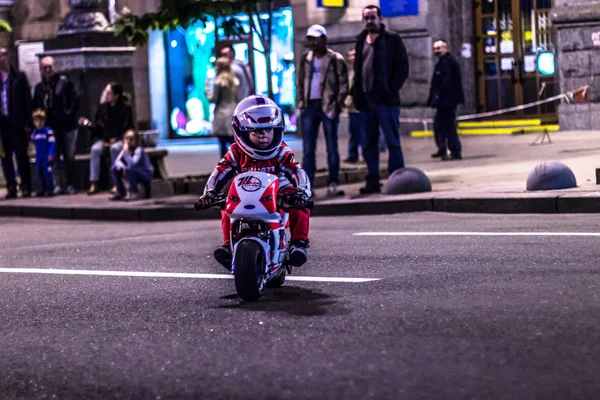 A child on a toy motorcycle rides on the street