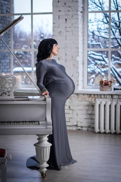 Femme Enceinte Dans Robe Grise Tient Près Piano Blanc Fenêtre — Photo