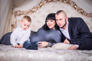 Baba ve anne ile oğlu yatağın üzerine oynamak.