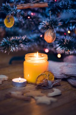 Bir mum Noel ağacının altında yanıyor, kurabiye, şeker, yün çoraplar ve Eldivenler Turnuvası'na yakın vardır.