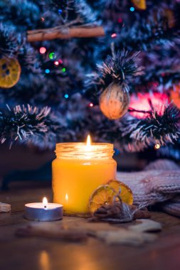Bir mum Noel ağacının altında yanıyor, kurabiye, şeker, yün çoraplar ve Eldivenler Turnuvası'na yakın vardır.