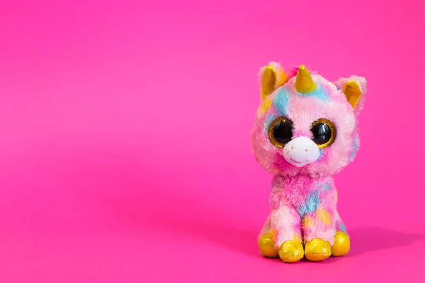 Oyuncak pembe Unicorn pembe bir arka plan üzerinde oturur.