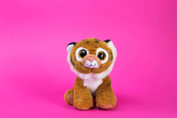 Toy cartoon lion king simba sits on a pink background.