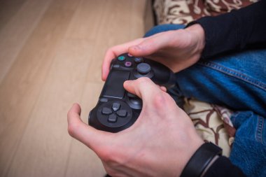 Adam üzerinde konsol oyun oyun çubuğu oynuyor.