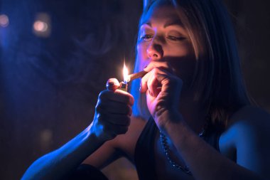 Güzel sarışın kız bir pencere ay ışığında, Sigara içiyor.