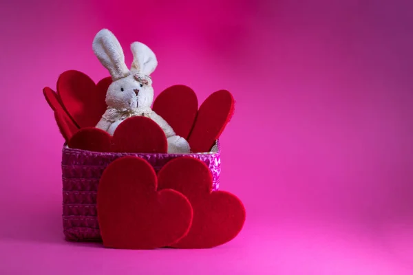 Toy Bunny in pink basket among Red hearts.