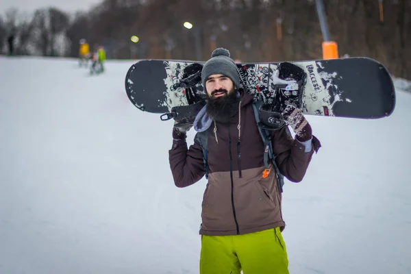 Snowboarder Maschio Barbuto Mantiene Tavola Sulle Spalle Uno Sfondo Neve — Foto Stock