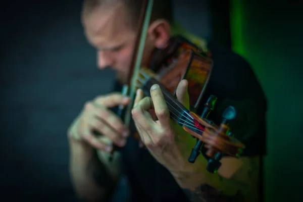 The violinist plays the violin. Brutal man with a beard playing the violin fatal simony. Close-up