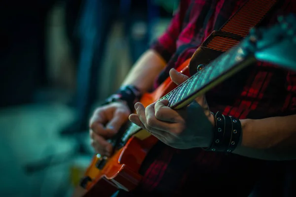 The man plays the guitar, close-up of the fingers on the strings.