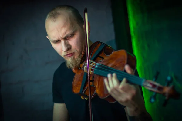 The violinist plays the violin. Brutal man with a beard playing the violin fatal simony. Close-up