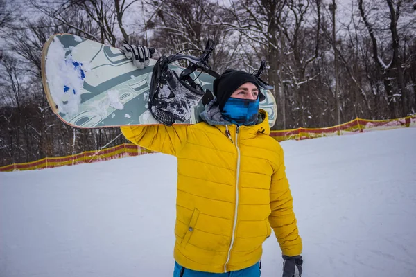 Snowboarder Μια Μάσκα Κατέχει Ένα Snowboard Στον Ώμο Του — Φωτογραφία Αρχείου