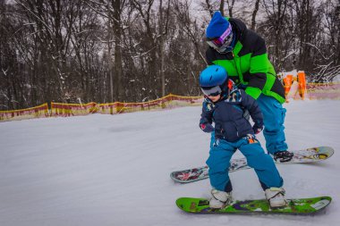 Baba snowboard tahtada binmek için son öğretir.