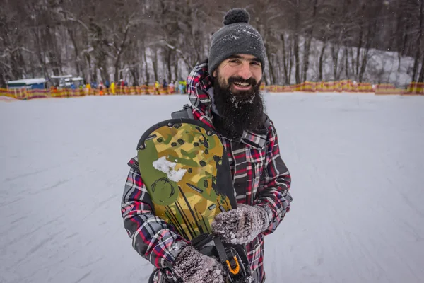 bearded male snowboarder with a board on snow background.