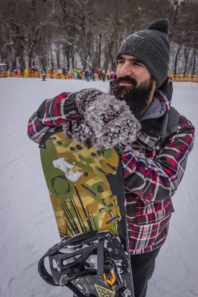 bearded male snowboarder with a board on snow background.