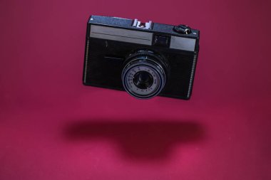 Havada uçan kırmızı zemin üzerine eski retro fotoğraf makinesi.