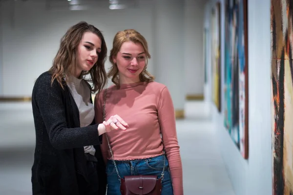 Two girls discuss paintings in Gallery of modern art — Stock Photo, Image