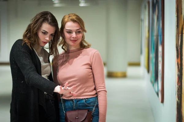 Дві дівчини обговорюють картини в галереї сучасного мистецтва — стокове фото