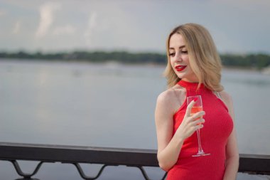 Bir kız şampanya tankı ile nehrin yanında duruyor.