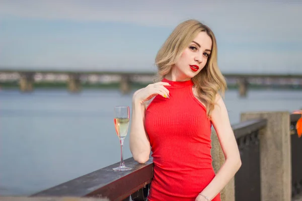 Une fille se tient près de la rivière avec un réservoir de champagne — Photo