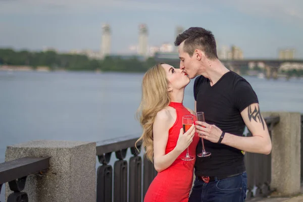 Um jovem casal bonito está em uma ponte junto ao rio — Fotografia de Stock
