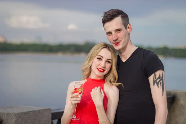 Um jovem casal bonito está em uma ponte junto ao rio — Fotografia de Stock