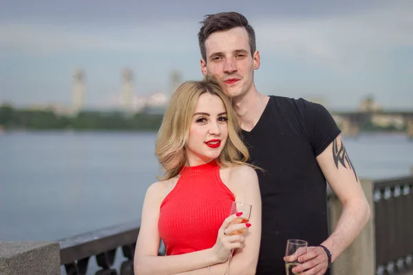 Um jovem casal bonito está em uma ponte junto ao rio — Fotografia de Stock
