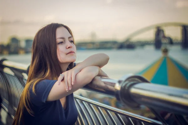 Una hermosa chica está en un muelle junto al río — Foto de Stock