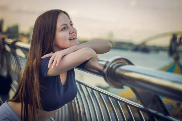 Une belle fille se tient sur une jetée près de la rivière — Photo