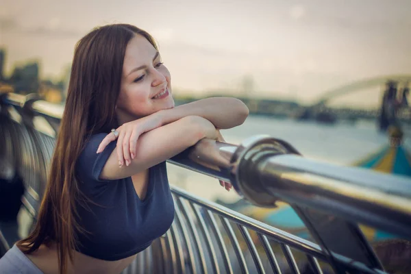 En vacker flicka står på en brygga vid floden — Stockfoto
