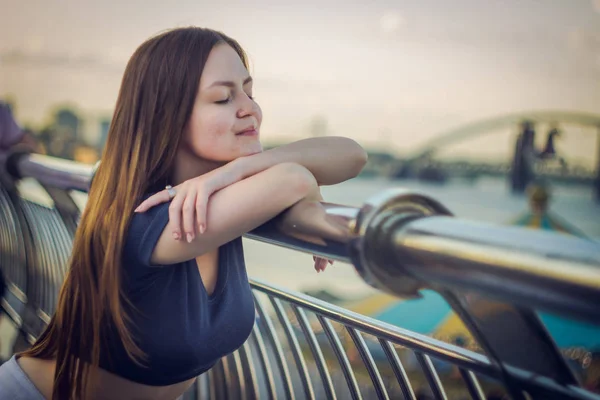Una hermosa chica está en un muelle junto al río — Foto de Stock