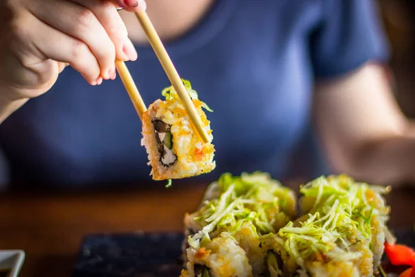 Girl eats Japanese vegetarian rolls