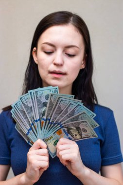 Elinde dolarlar olan genç bir kadın, beyaz arka planda soyutlanmış.
