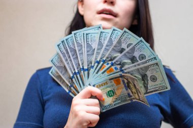 Elinde dolarlar olan genç bir kadın, beyaz arka planda soyutlanmış.