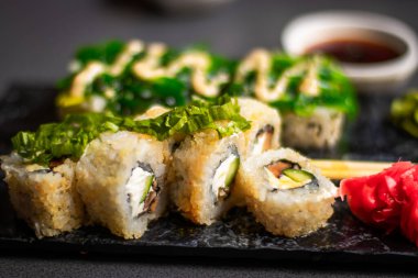 Yakından bakınca bambu çubuklarını soya sosuyla ıslatırken nigiri karidesli tutuyor. Lokantada ahşap tepside suşi hazırlarken Nigiri 'yi soya sosuna batırmak. Japon mutfağı kavramı.
