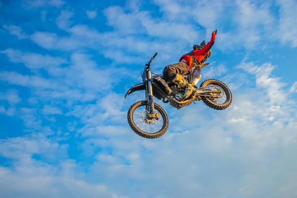 モトクロスライダー雲と青い空をジャンプします — ストック写真