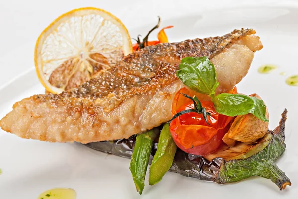 Izgara sebze bir yastık üzerinde kızarmış beyaz balık parçası. Yakın çekim.