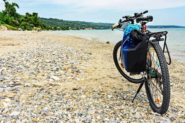 Bicicleta de montaña con bolsa junto al mar aparcada en la playa . — Foto de Stock