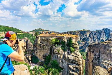 Tourist taking a picture Holy Monastery of Varlaam - one of Eastern Orthodox monasteries located in rock formation Meteora.  clipart