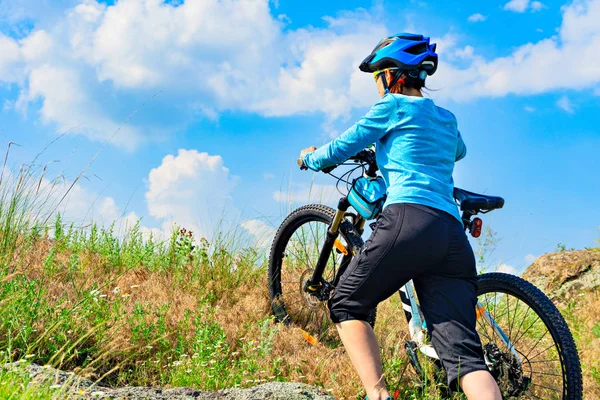 Mujer ciclista empujando su bicicleta por una pendiente empinada . — Foto de Stock