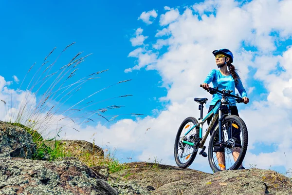 Mujer ciclista se para en la cima de la colina con su bicicleta de montaña . — Foto de Stock