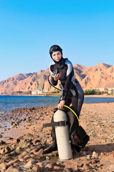 Vrouwelijke duiker controleren van haar uitrusting aan de kust voor het duiken. — Stockfoto