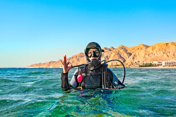 Woman diver floated on the surface of the sea and shows a hand sign that all is well. — ストック写真