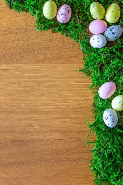 easter frame from natural green moss and easter eggs on a wooden table