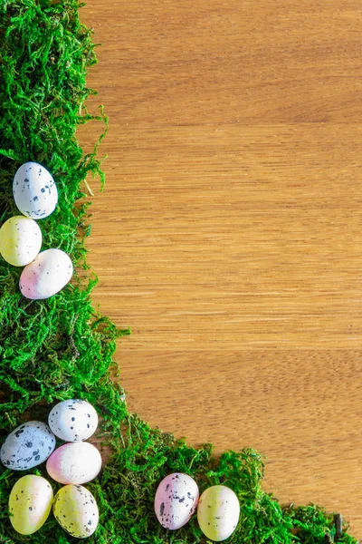 easter frame from natural green moss and easter eggs on a wooden table