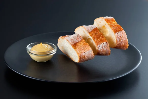 신선한 프랑스 버 게 트 빵 슬라이스 검은 접시 위에 공중에 뜨게. 어두운 배경에 빵 바게트의 창조적인 샷 스톡 이미지